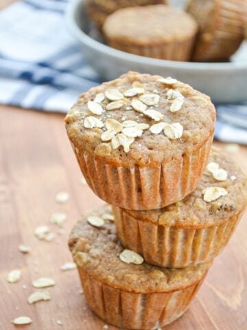 A stack of three muffins with oats sprinkled on top.
