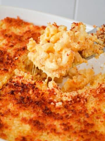 A close up of macaroni and cheese coming out of a casserole dish.
