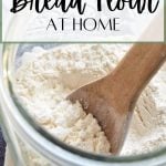 A big jar of homemade bread flour with a wooden spoon.