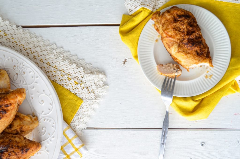 A plate of chicken, and a small plate with a single baked chicken breast.