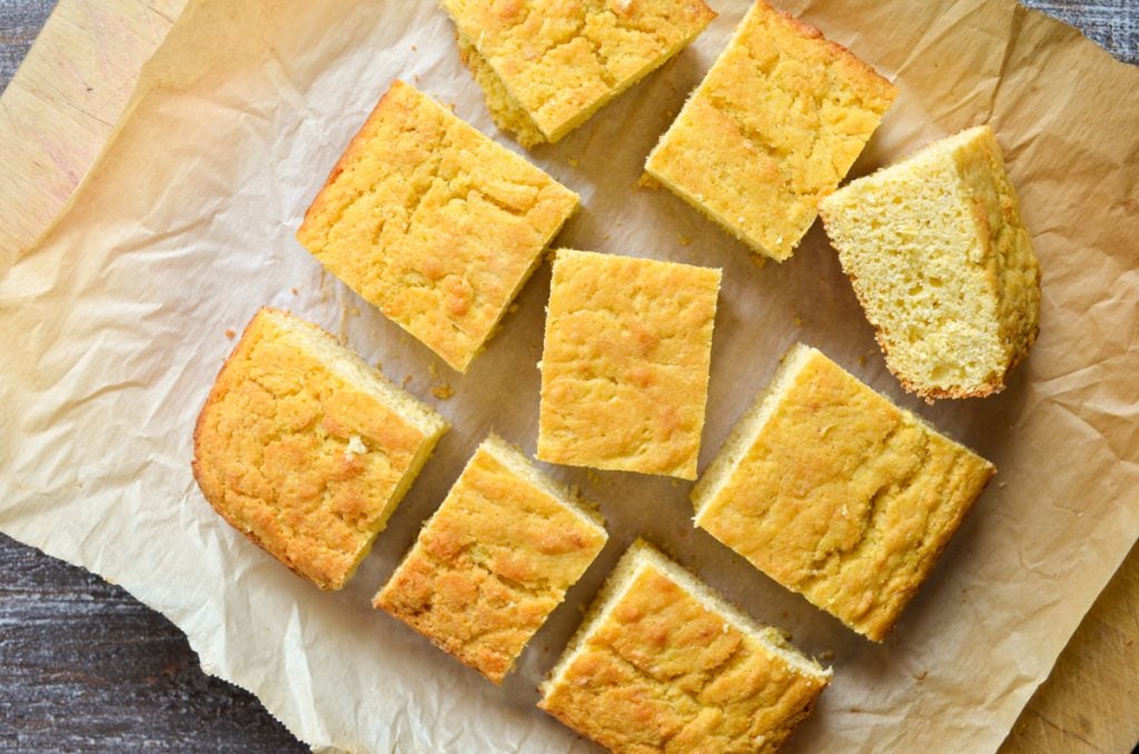 9 squares of baked cornbread on a piece of parchment paper.