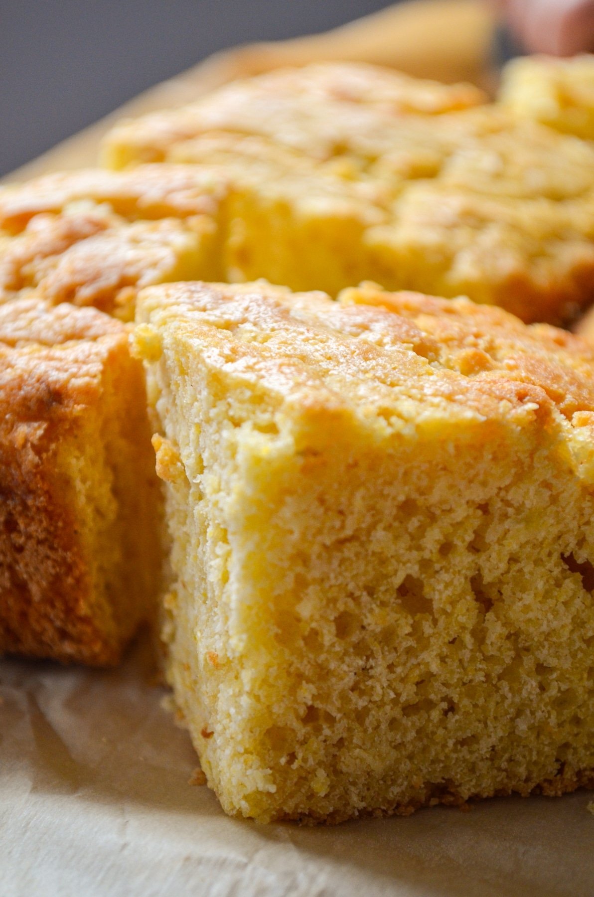 A close up of buttermilk cornbread on a parchment paper surface.