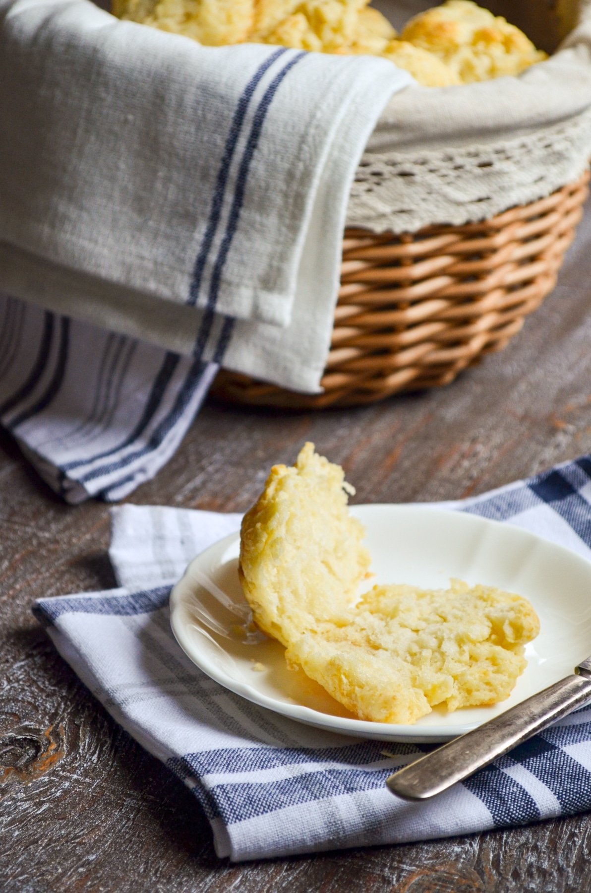 A biscuit cut open, with a basket of biscuits in the background