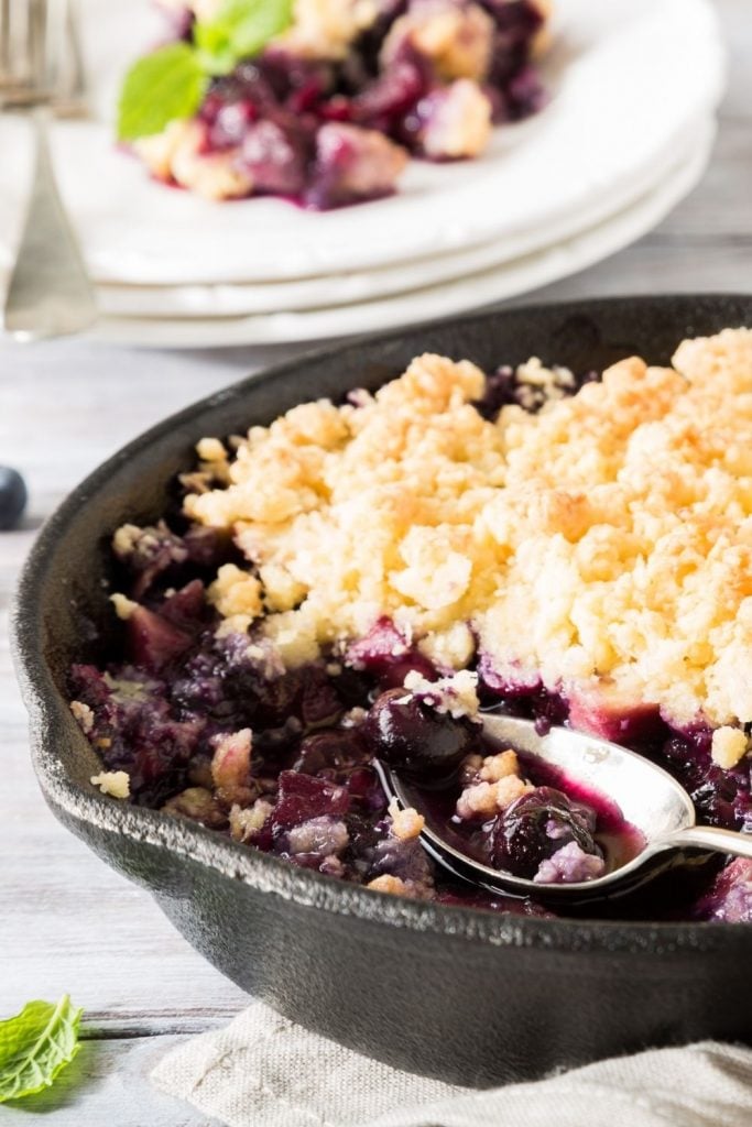 A cast iron skillet with a blueberry crumble.