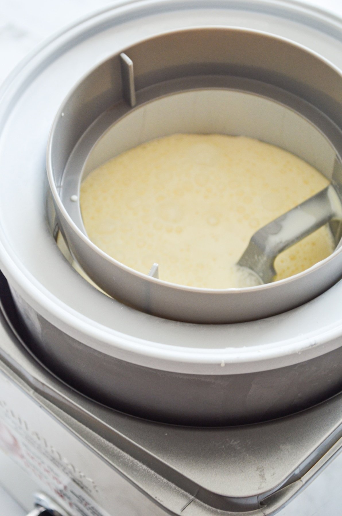 An ice cream maker with an ice cream base added into the frozen bowl portion.