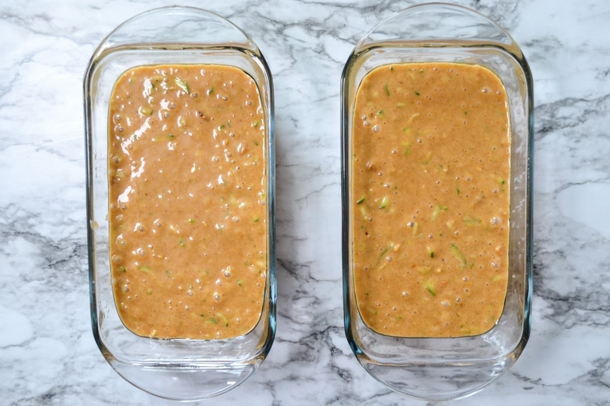 Two loaves of sourdough zucchini bread in glass loaf pans.