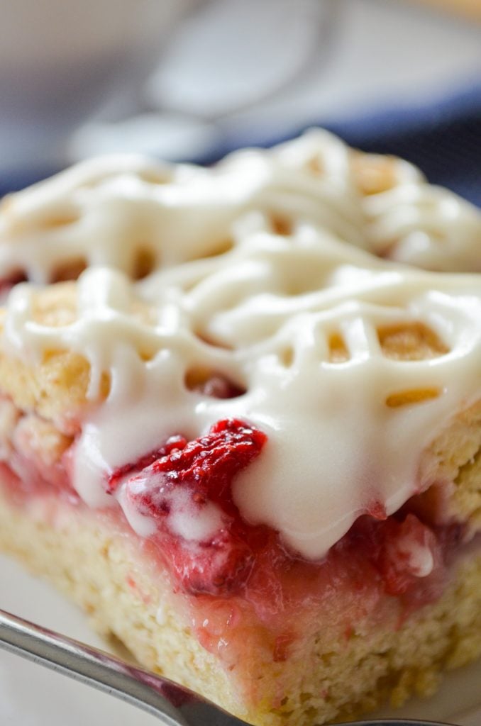 A big slice of strawberry oatmeal crumb bar, with a icing drizzle on top.