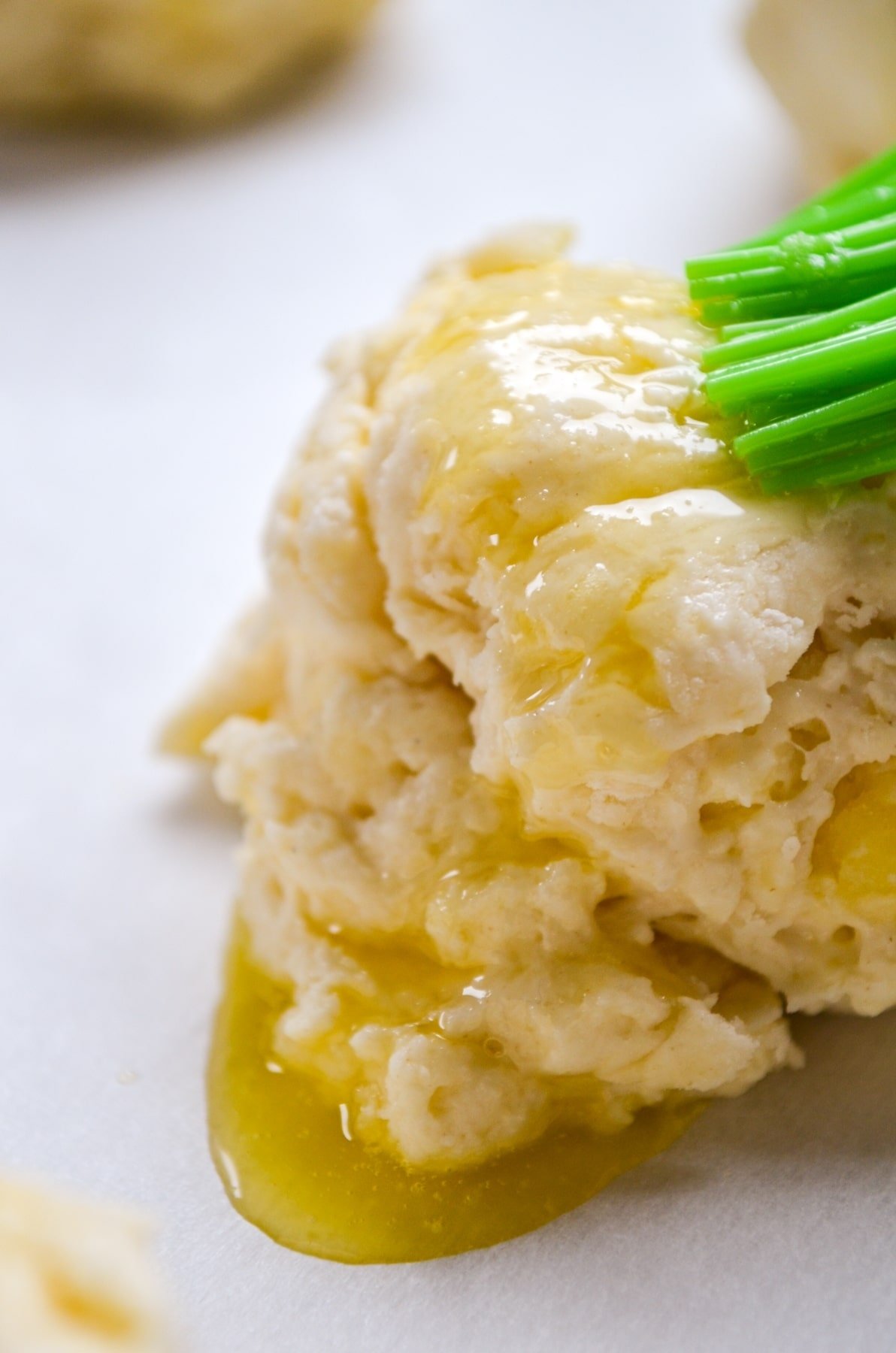 A drop biscuit being brushed with melted butter.