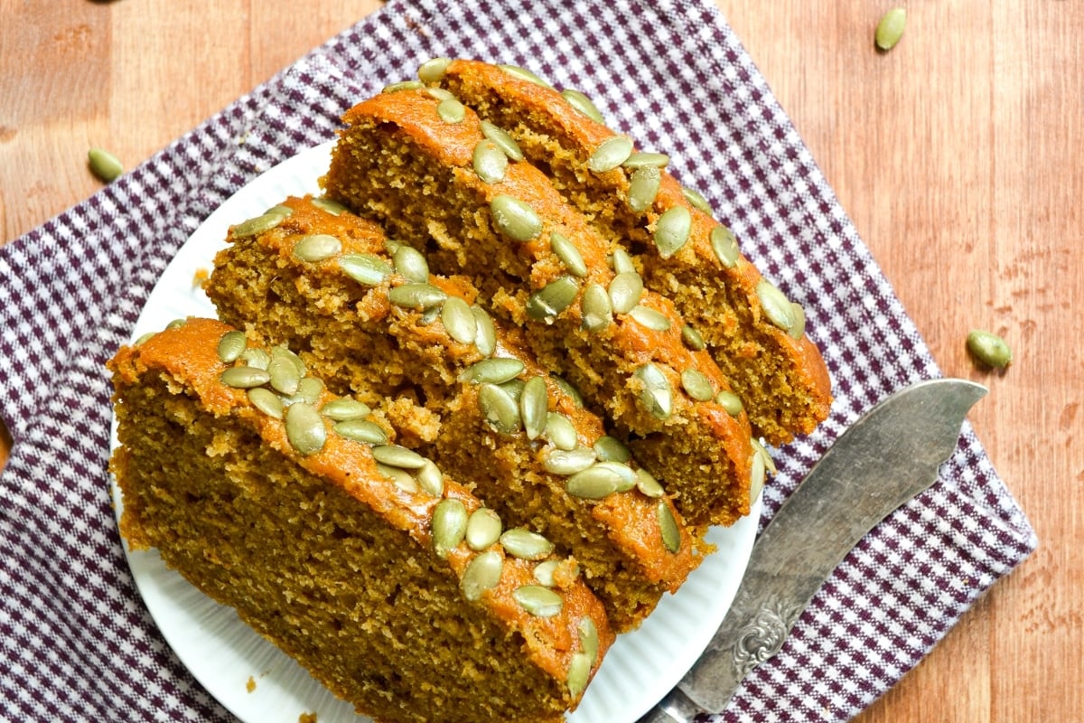 Several slices of pumpkin loaf, topped with pepitas.