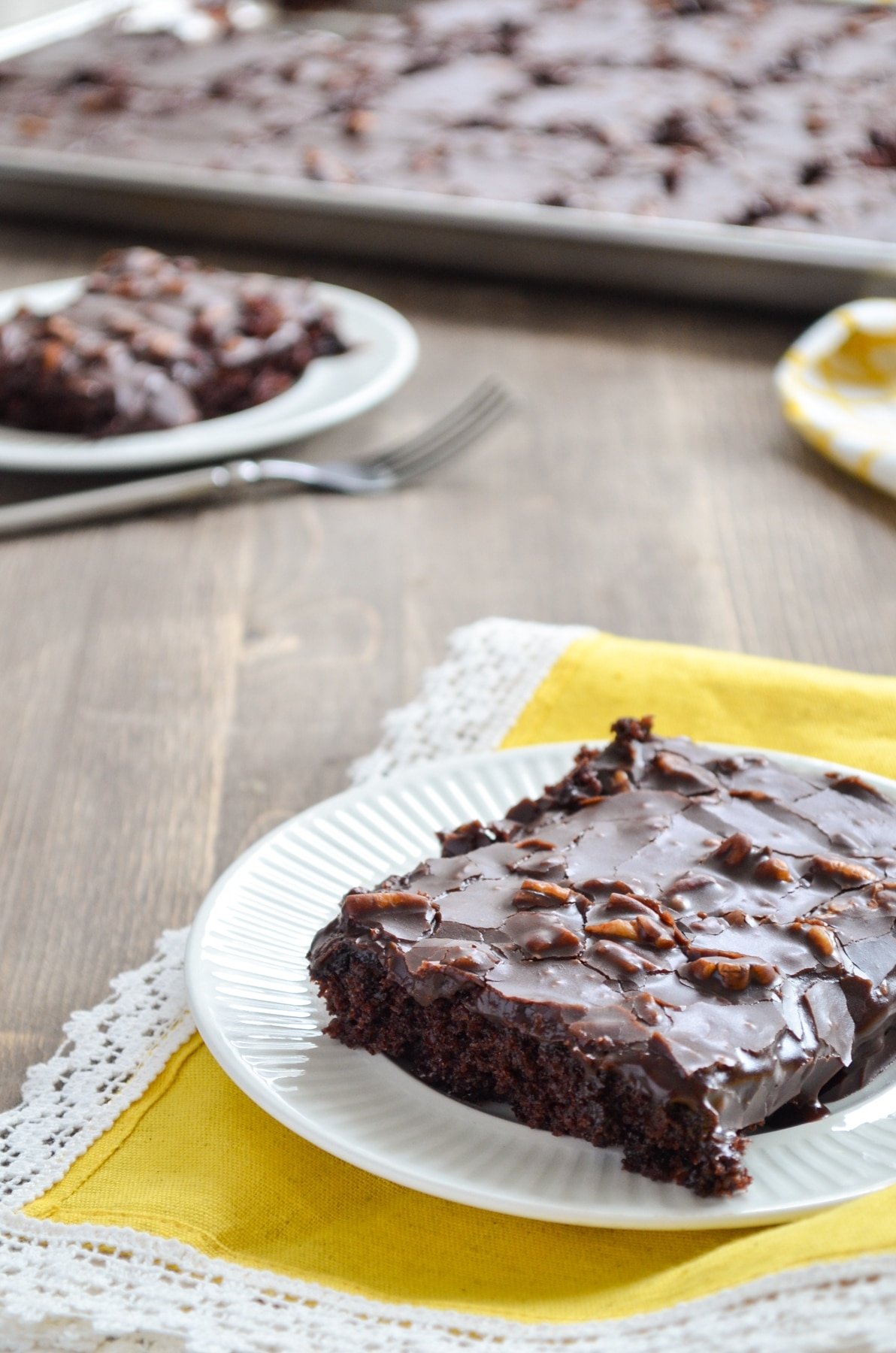 A slice of sourdough texas sheet cake, with the sheet pan in the background.