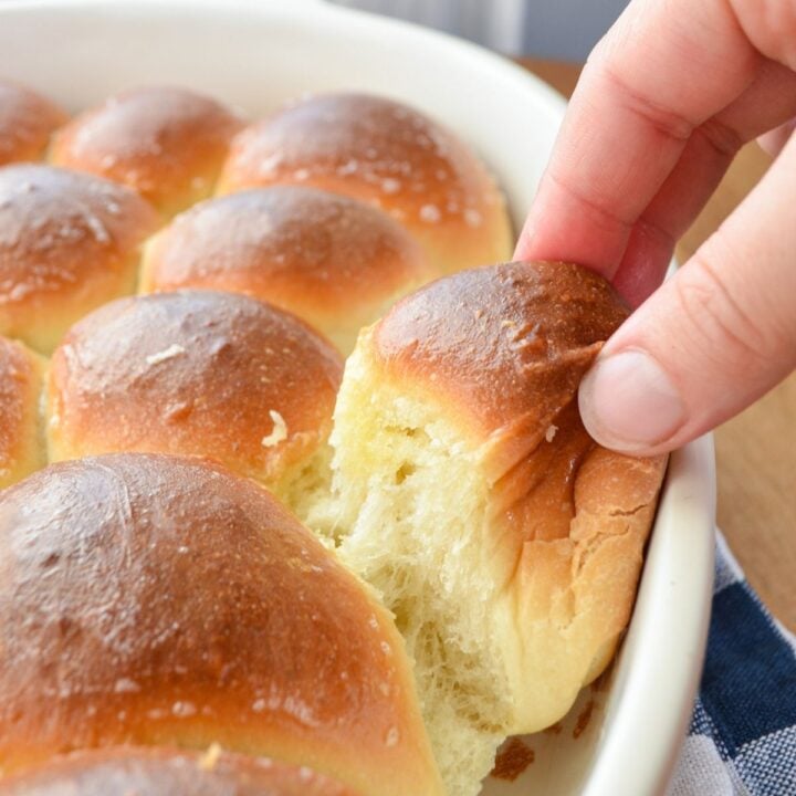 A warm baked roll being pulled out of a baking dish.