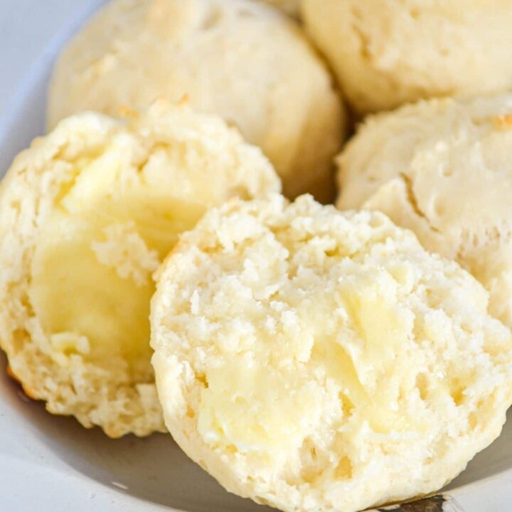 A close up of dinner rolls on an enamel plate.