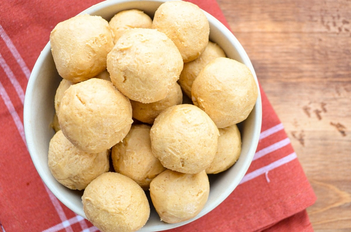 A bowl of no bake peanut butter balls on a cloth napkin.