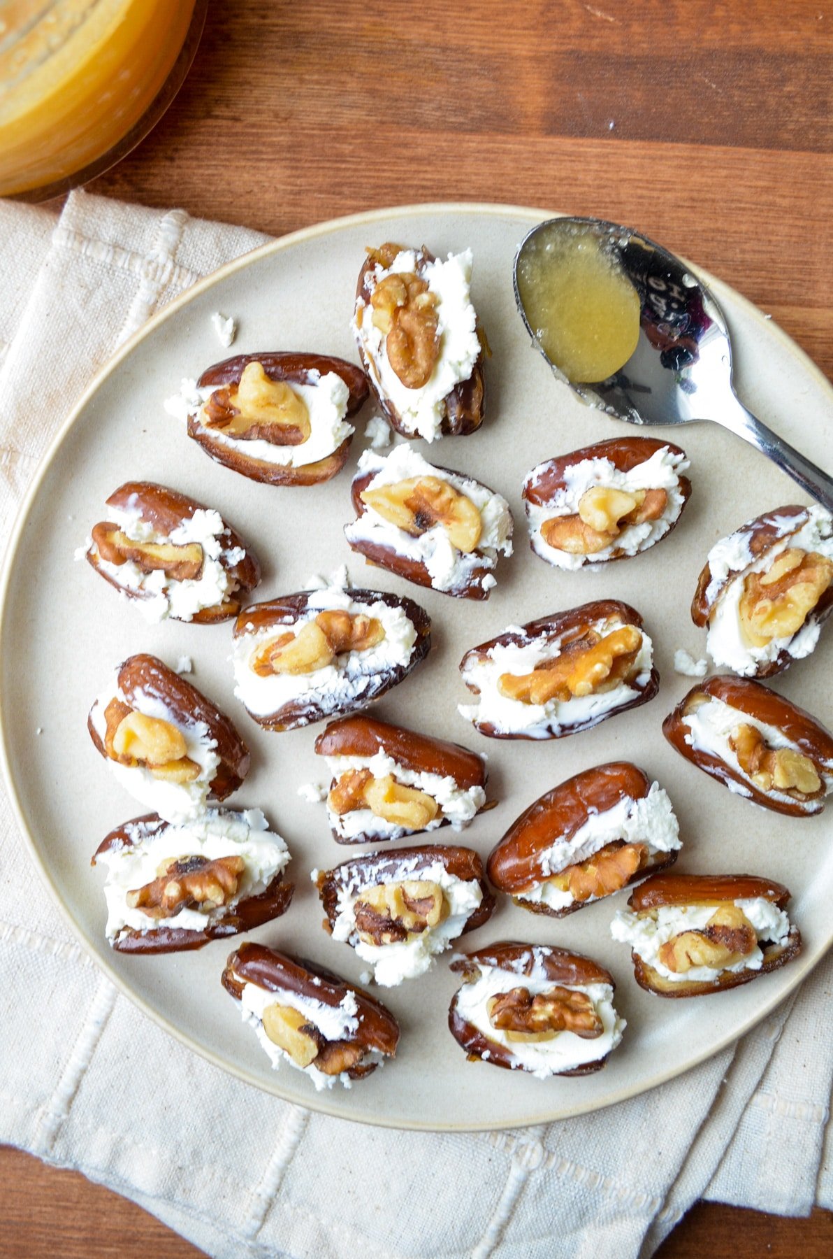 A plate of stuffed dates, with a honey spoon on the side.