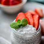 A jar of kefir chia pudding, garnished with mint and strawberries