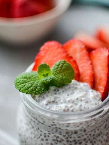 A jar of kefir chia pudding, garnished with mint and strawberries