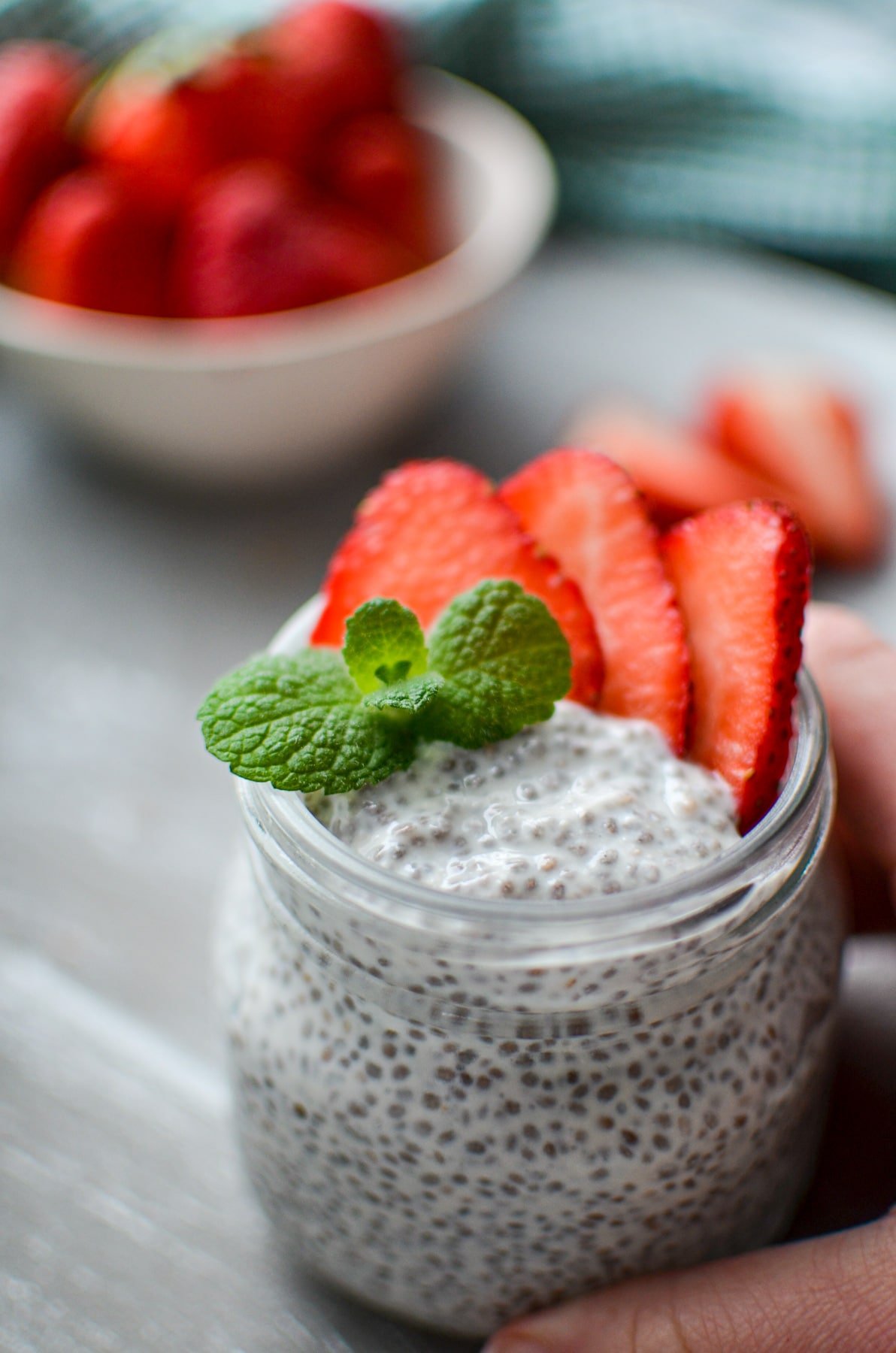 A hand reaching in to grab a jar of chia pudding.