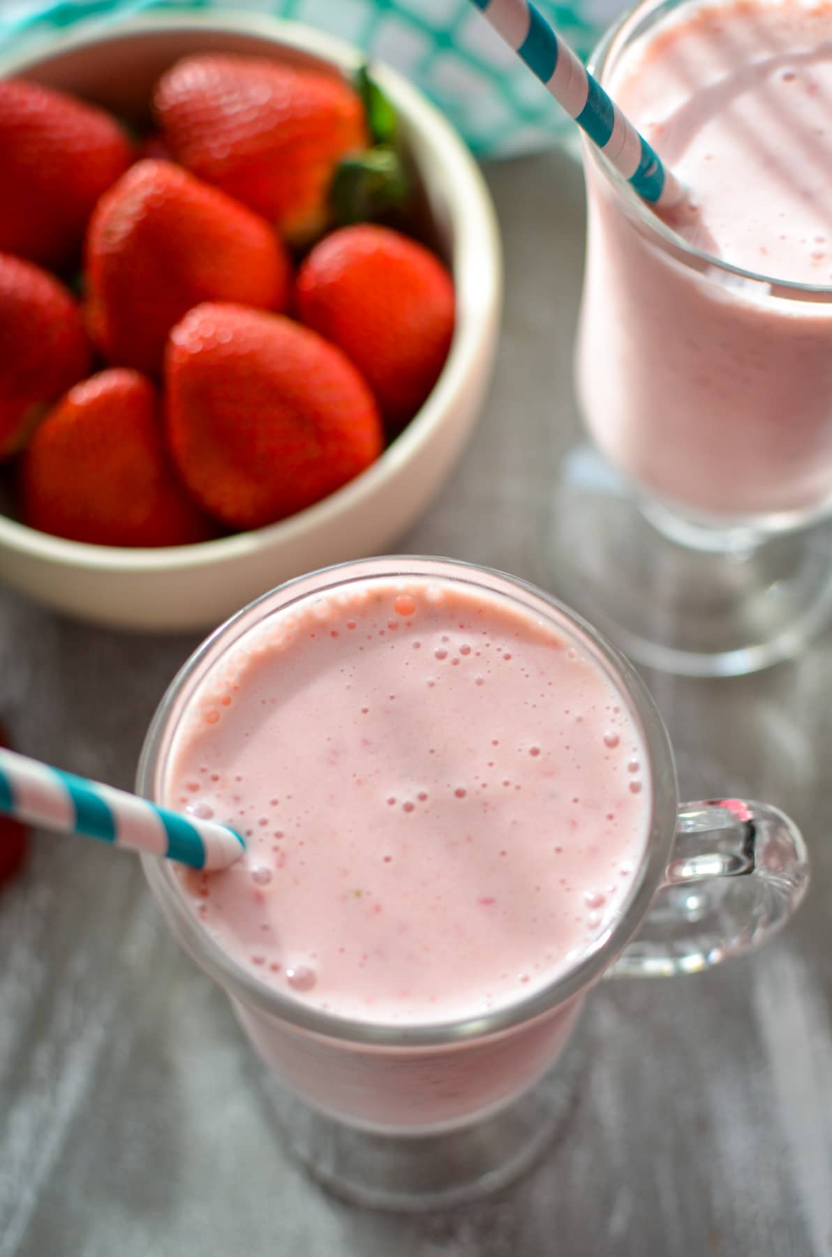 A strawberry smoothie with a teal paper straw