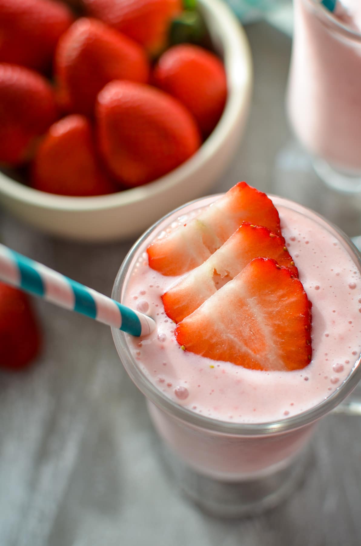 A glass of strawberry smoothie, garnished with sliced fresh strawberries.