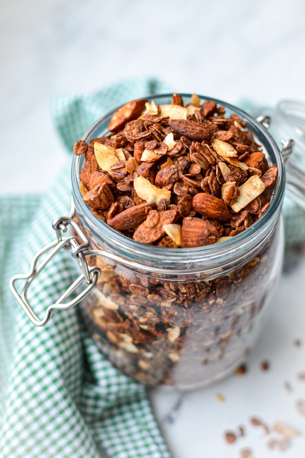 A jar of granola resting on a green gingham napkin.