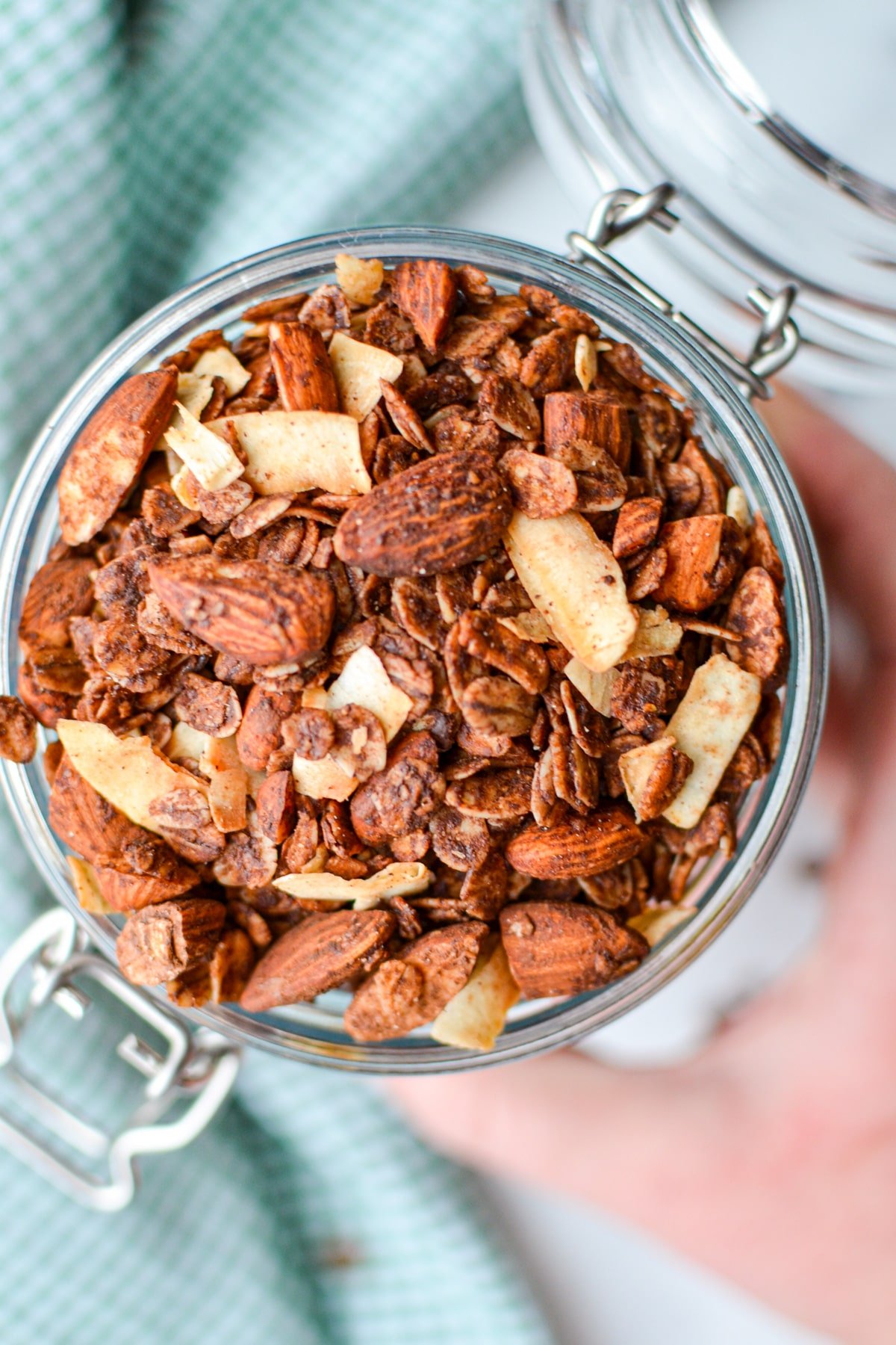 A hand reaching for a jar of granola.