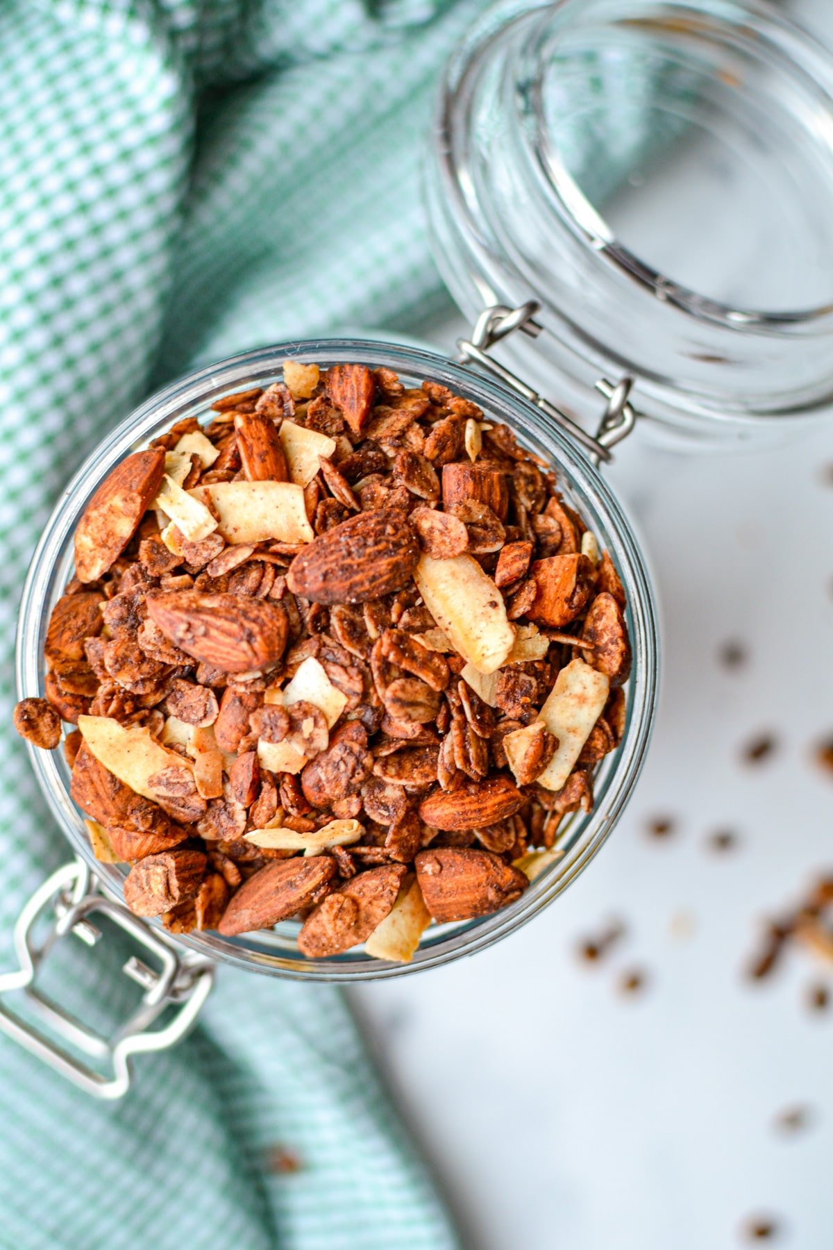 An overhead shot of a jar of granola with a green gingham napkin.