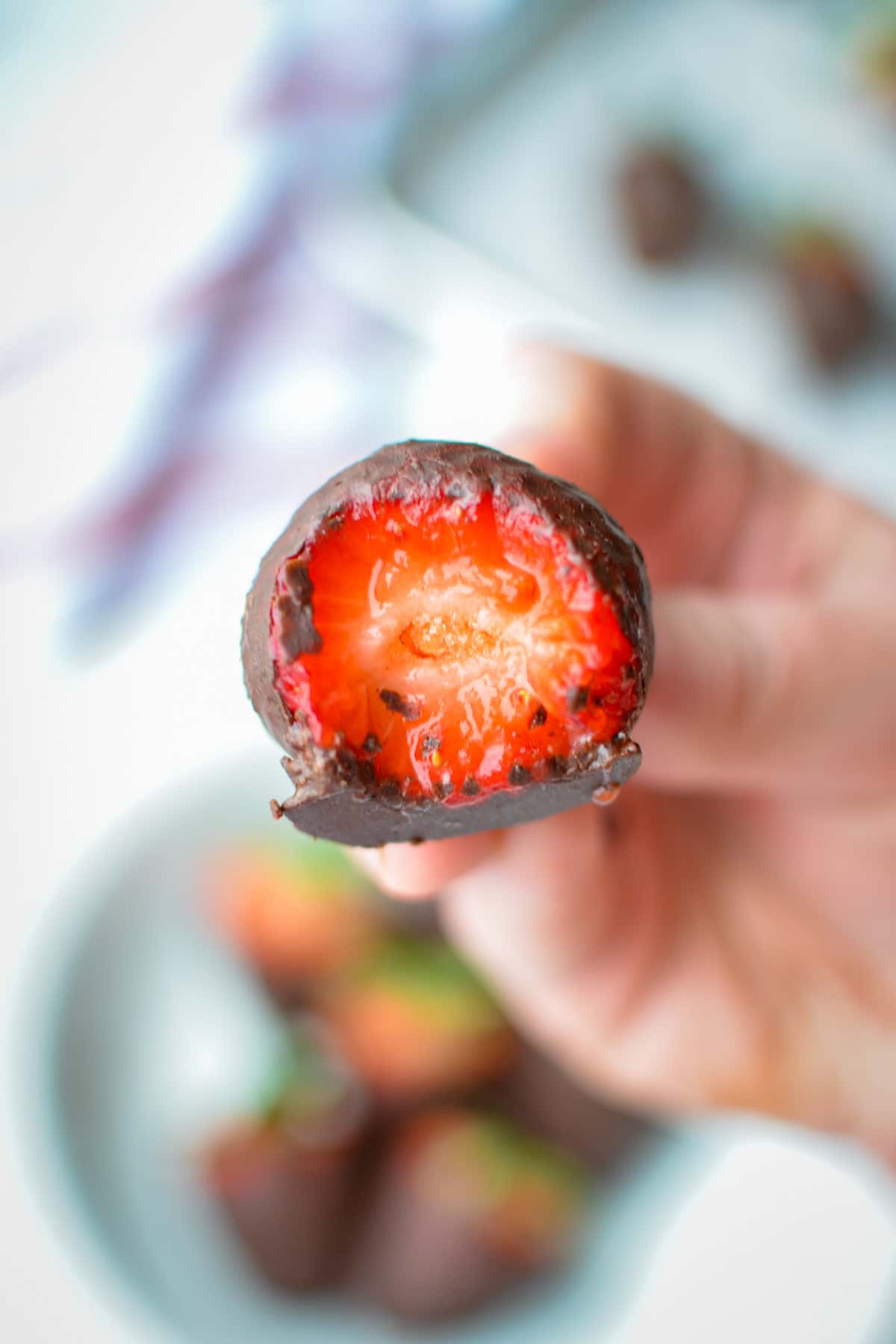 A chocolate covered strawberry with a bite taken ot of it. 