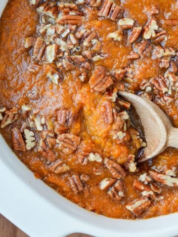 A baking dish of healthy sweet potato casserole with a pecan topping.