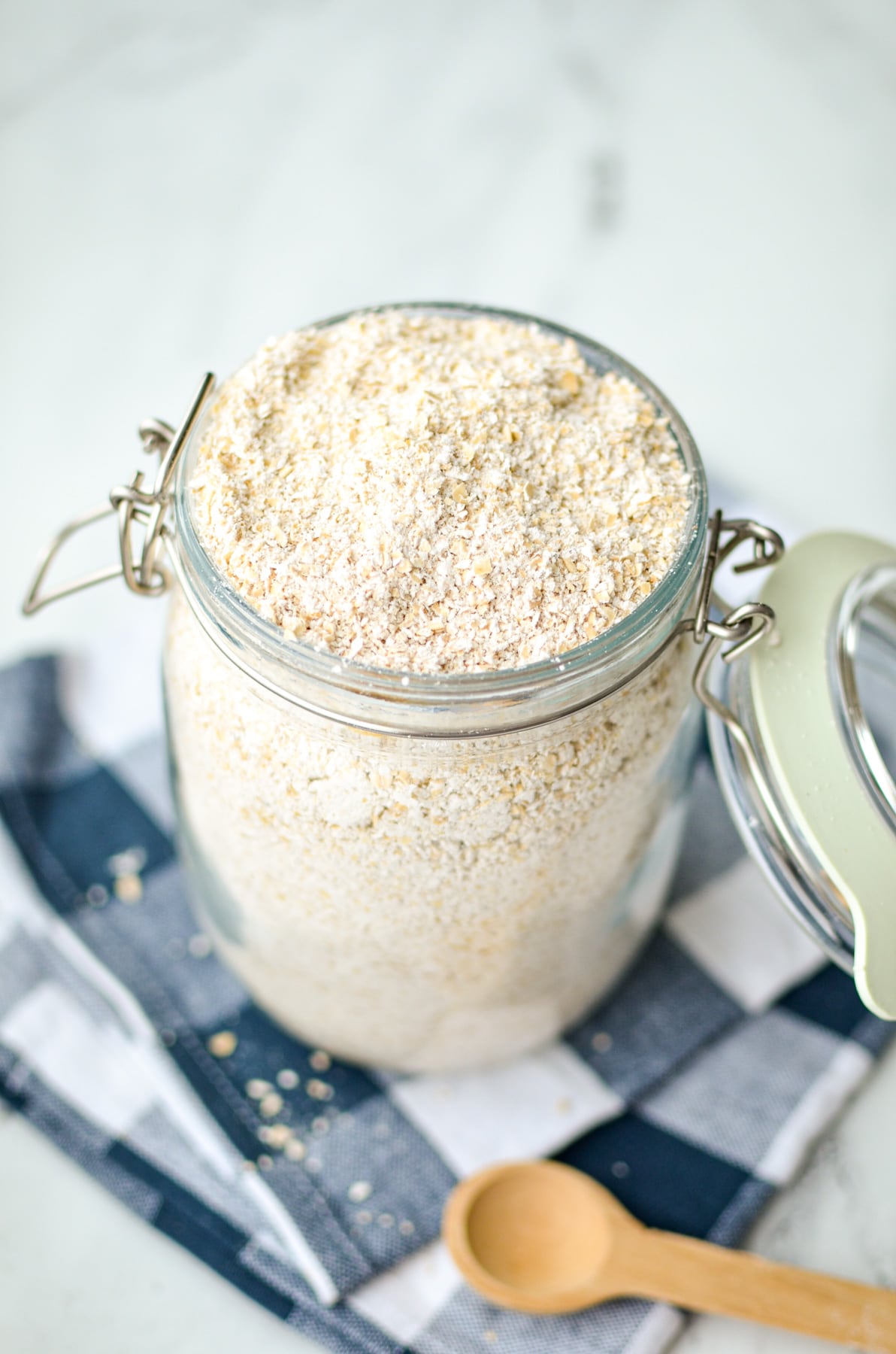 A jar of sprouted out flour on a blue check napkin.