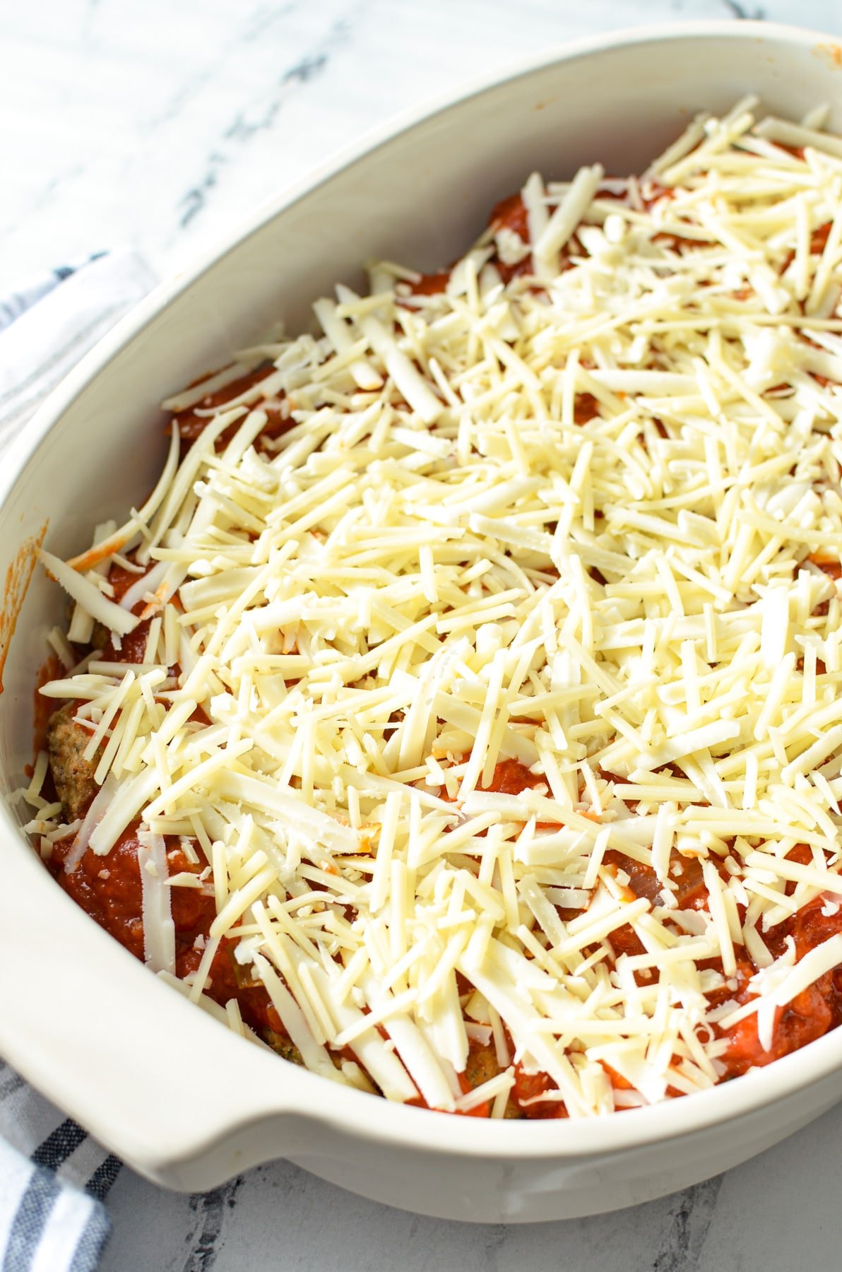 A meatball casserole topped with marinara and cheese.