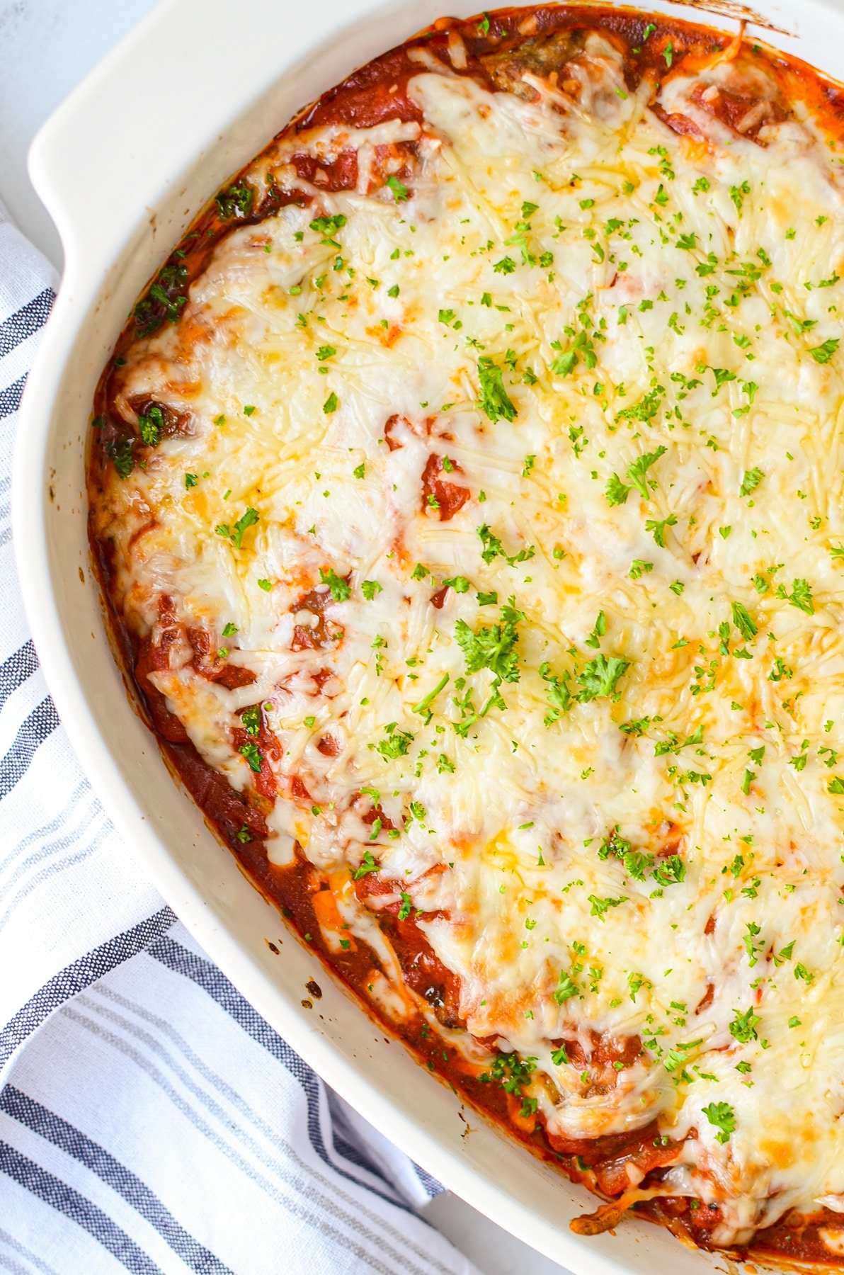 A baked meatball parmesan casserole, topped with fresh chopped parsley.