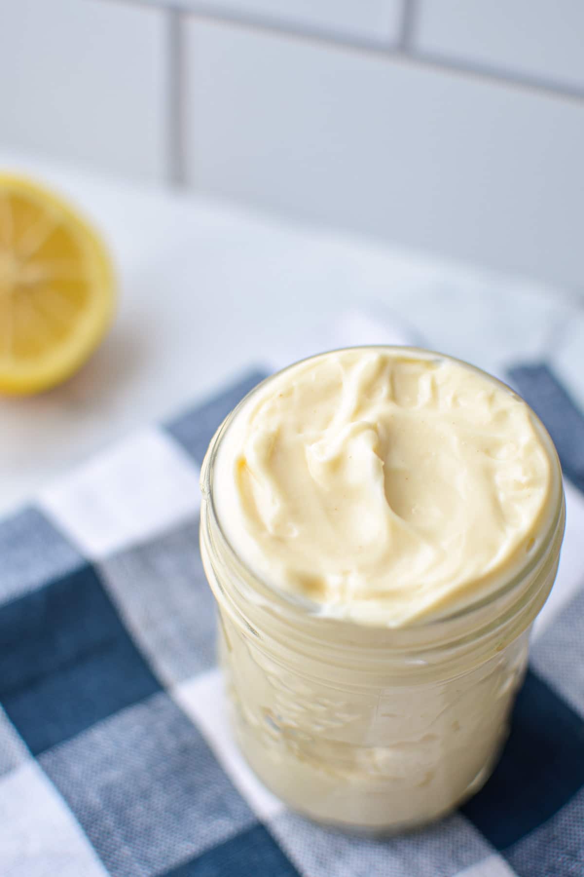 A jar of homemade avocado oil mayo, resting on a blue check napkin.