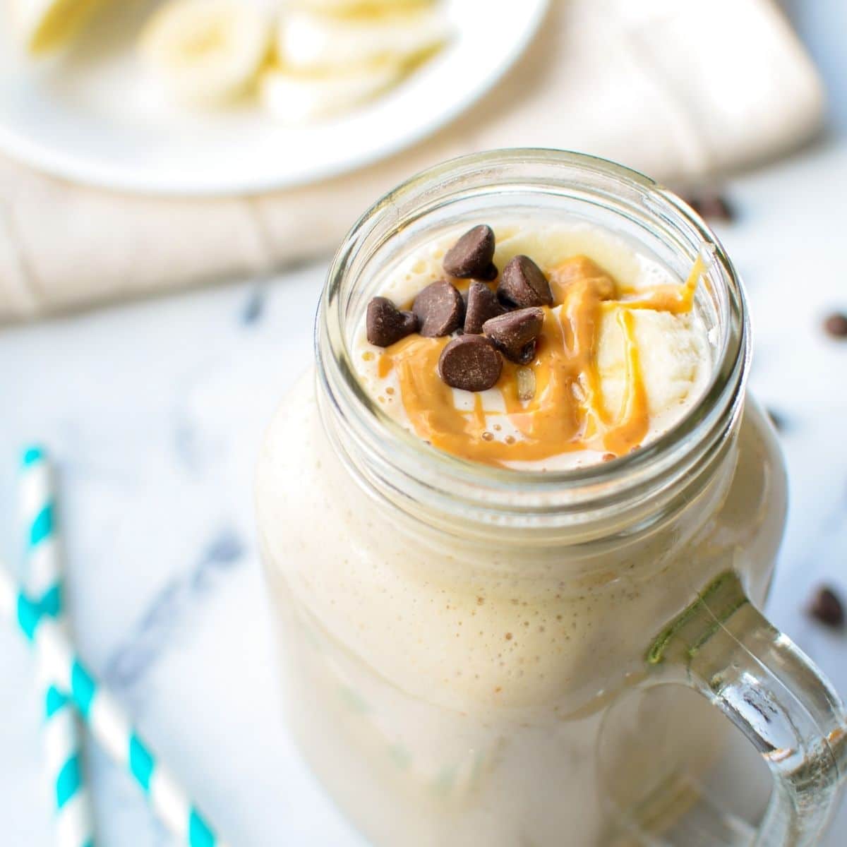 A kefir smoothie with banana and peanut butter, drizzled with peanut butter and a few chocolate chips sprinkled on top.