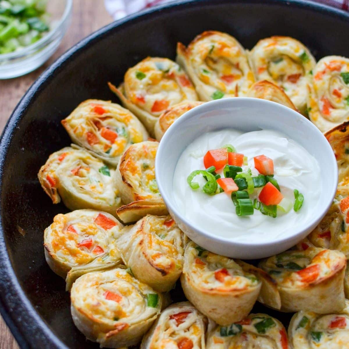 A cast iron skillet full of antojitos and a sour cream sauce