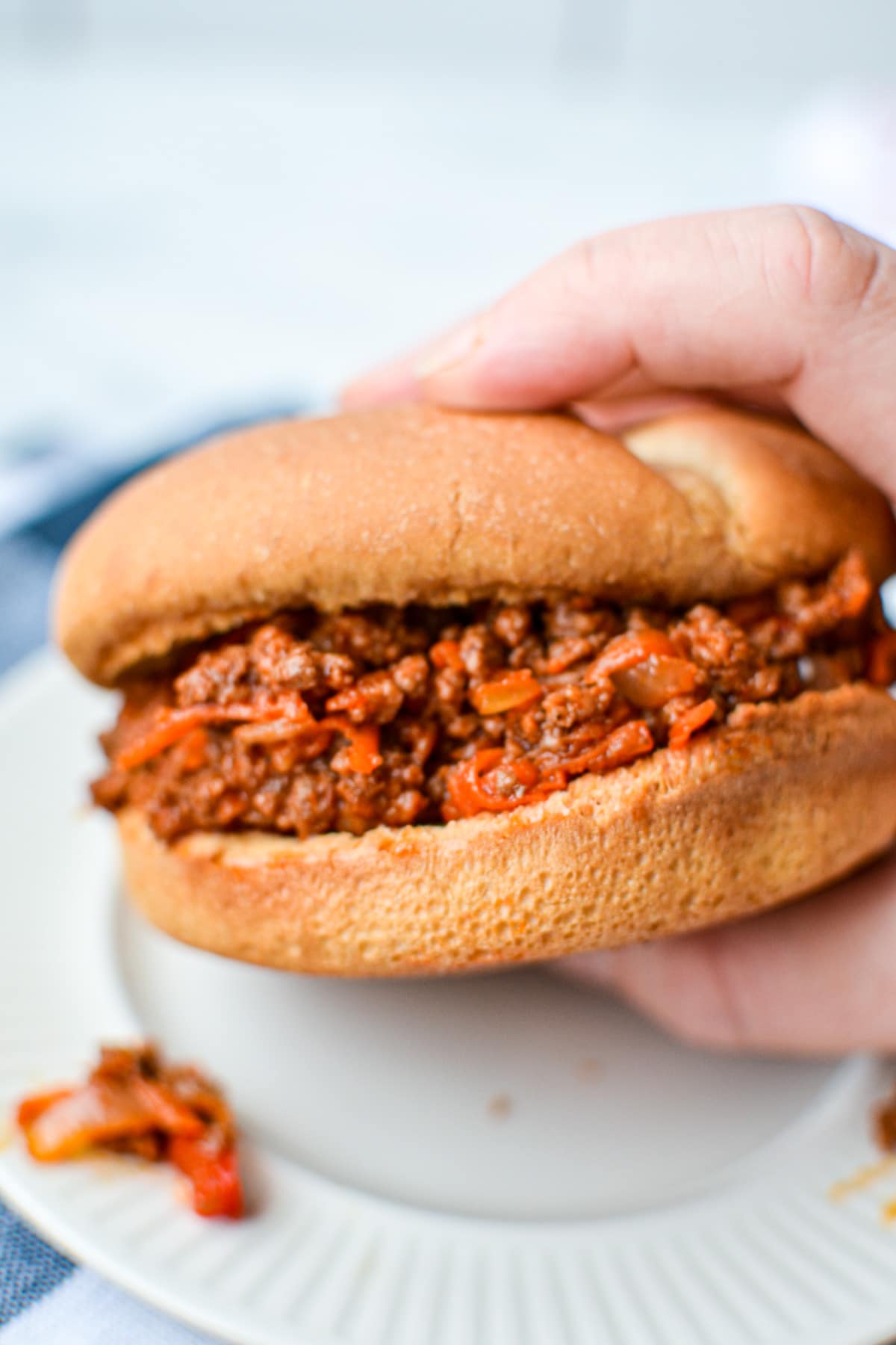 A close up of a sloppy joe with shredded carrot inside.