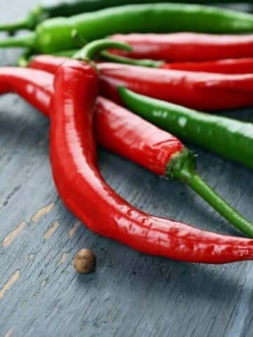 Several hot peppers on a wood surface.