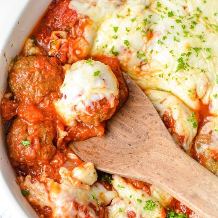 A dish of baked meatballs with marinara sauce and mozzarella and parmesan cheeses.