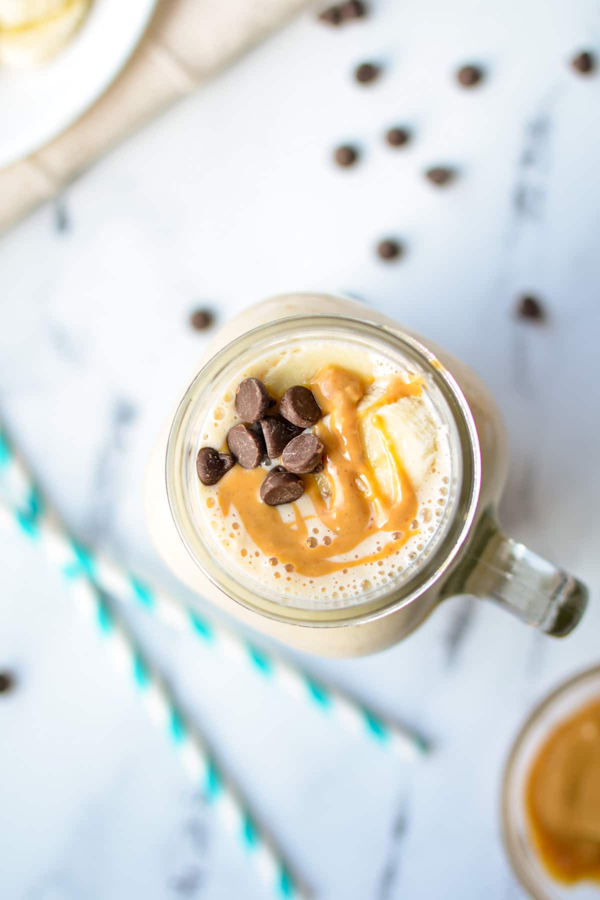 An overhead shot of a kefir smoothie with banana, peanut butter, and sprinkled with chocolate chips.