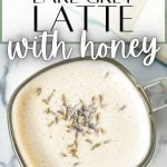 An overhead shot of a mug of a creamy latte, garnished with dried lavender buds.