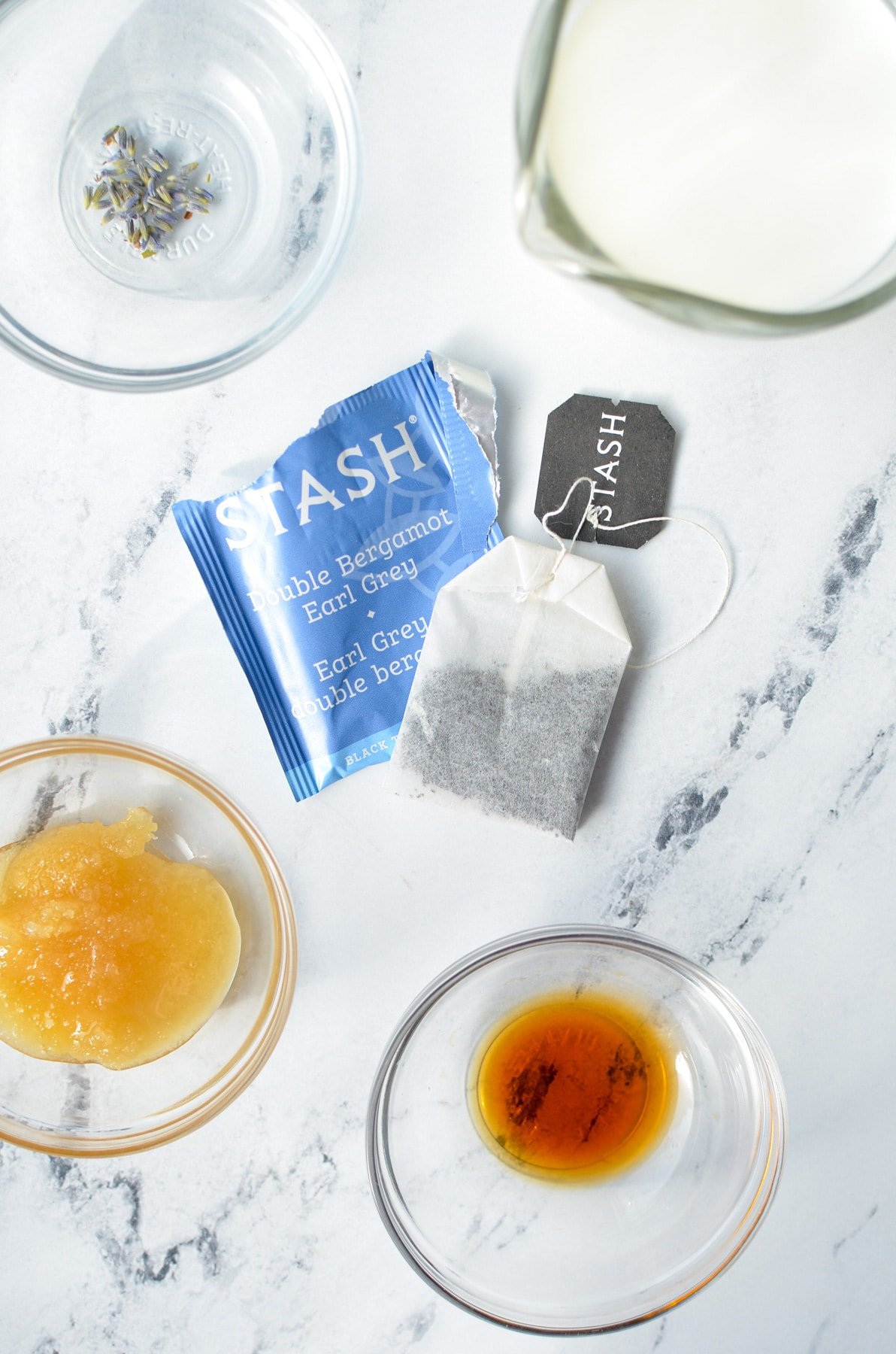 The ingredients needed to make an Earl Grey Tea Latte, including earl grey tea, milk, and lavender buds.