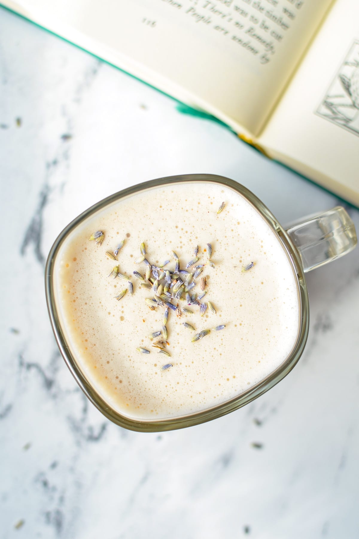 A glass mug filled with a London Fog Latte, with a book in the background.