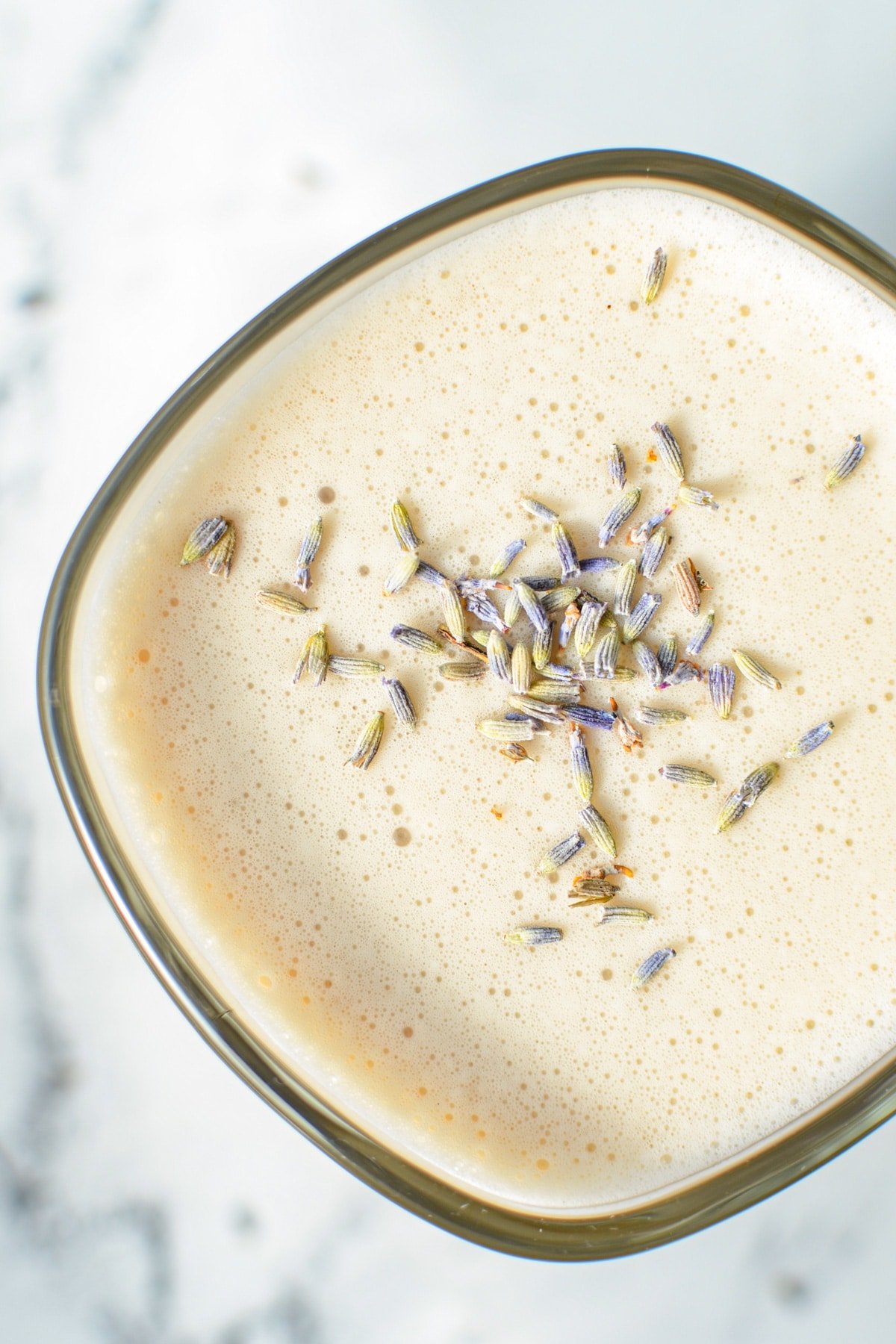 An overhead shot of a glass mug of London Fog Tea Latte, garnished with dried lavender buds.