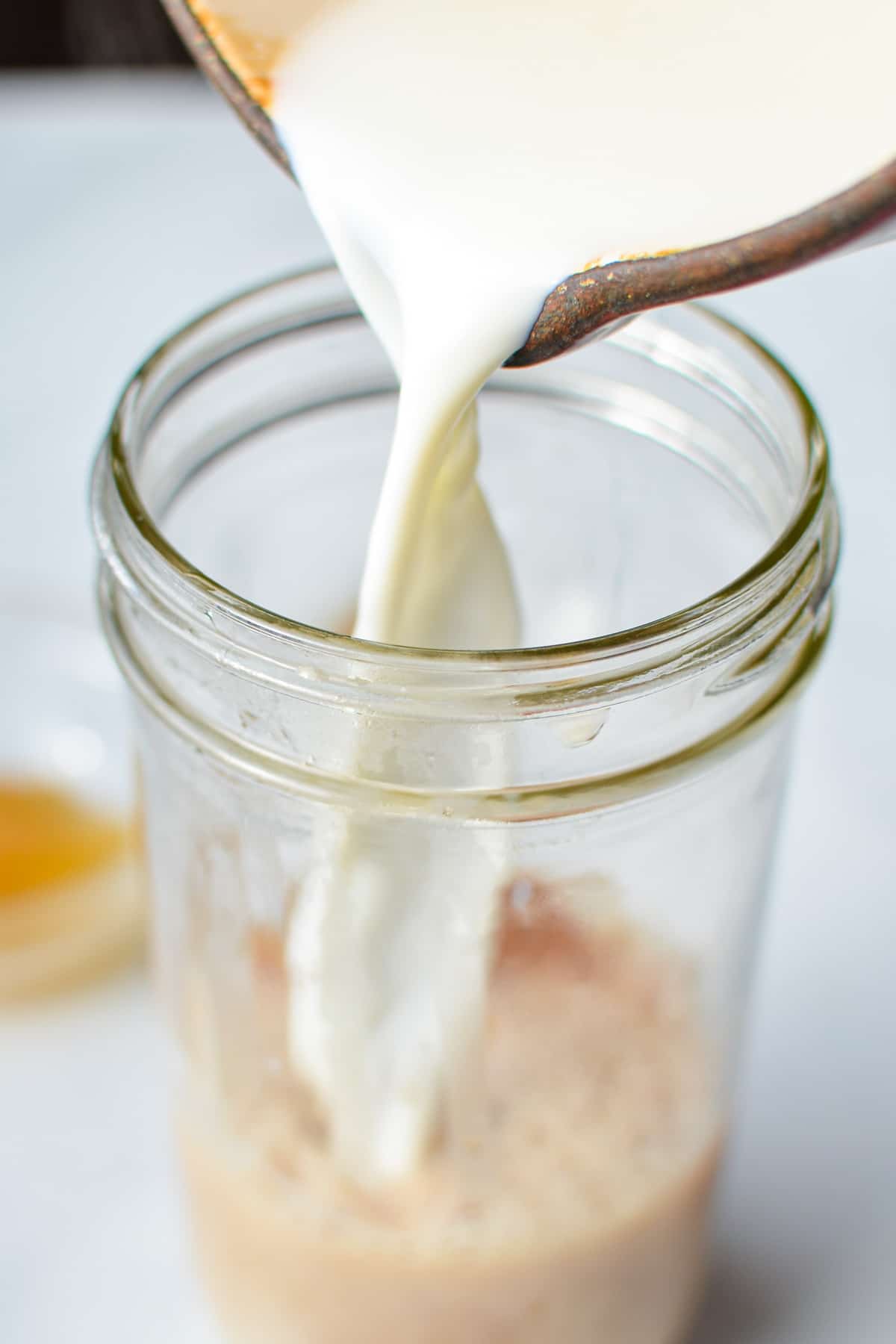 Adding milk to a jar of brewed tea.