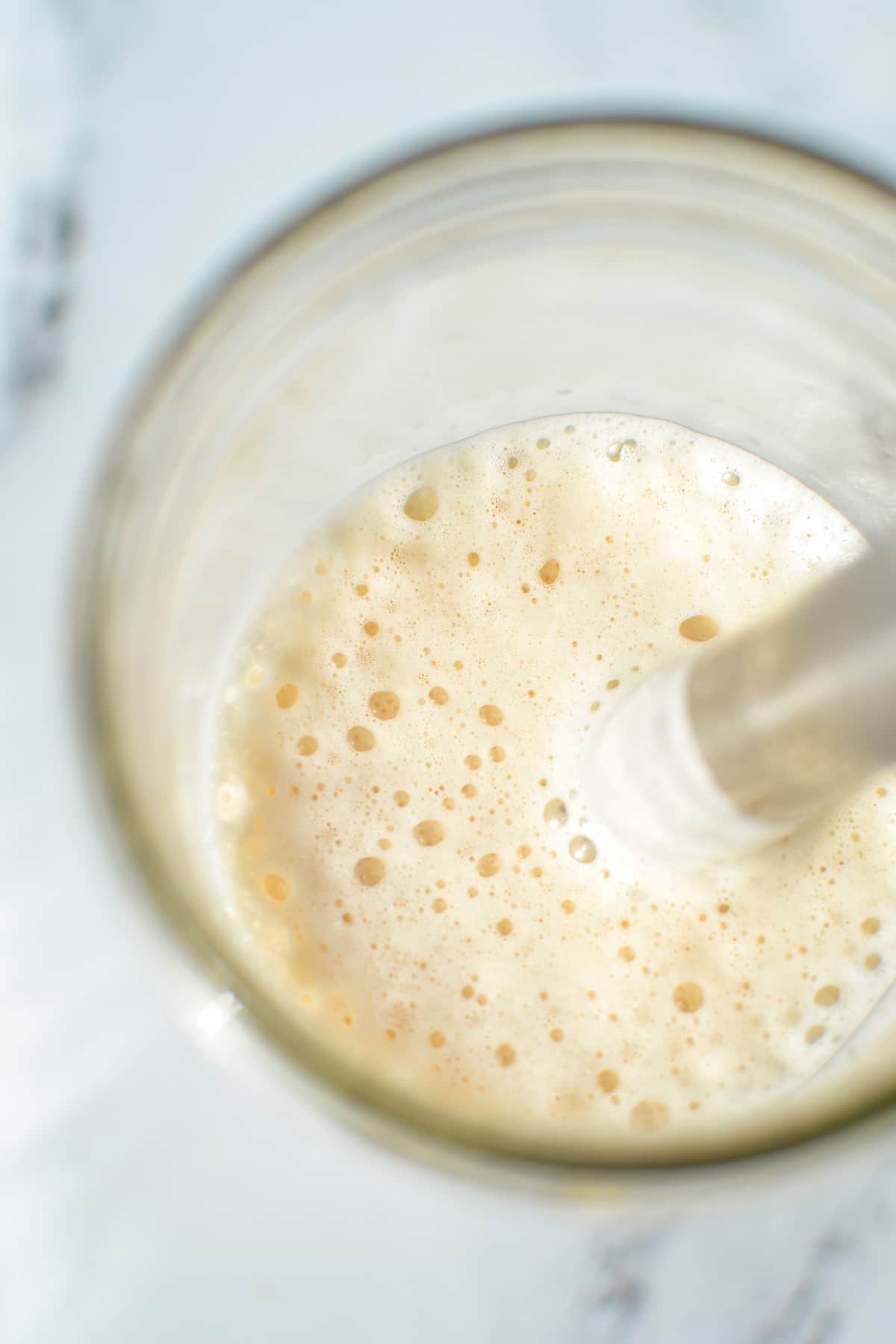 A frothy mixture inside of a wide mouth mason jar.