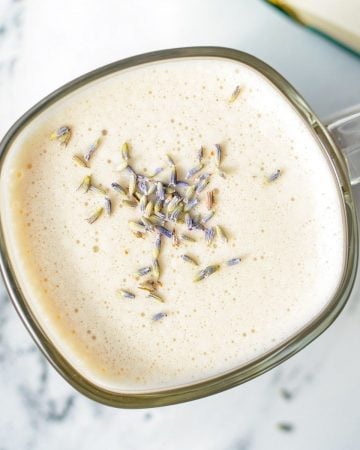 A glass mug of a London Fog Latte, with dried lavender buds.