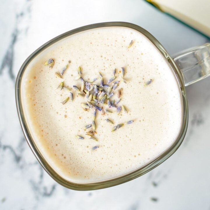 A glass mug of a London Fog Latte, with dried lavender buds.