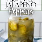A jar of fermented jalapeno slices, on a blue check napkin.