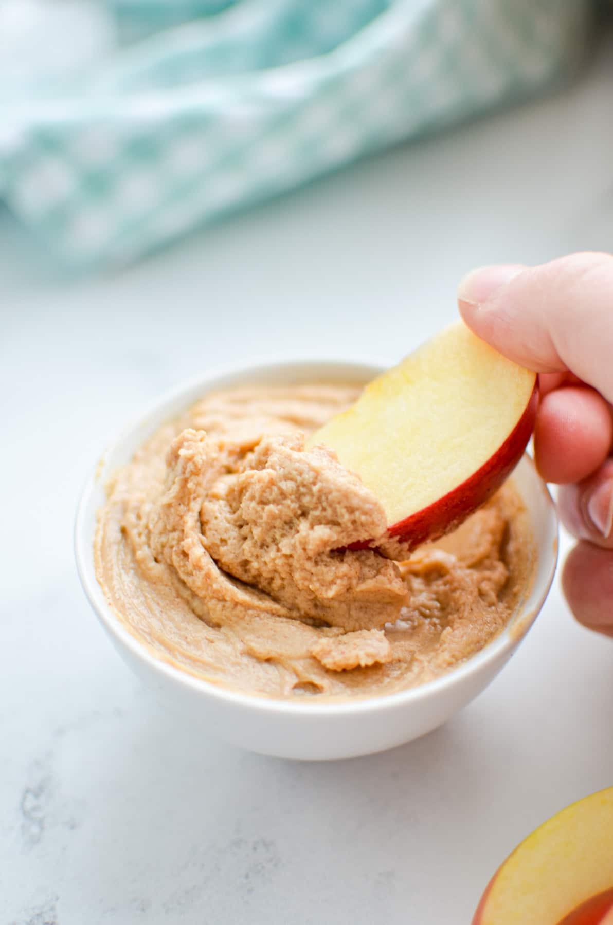 Dipping an apple slice into a prepared peanut butter dip.