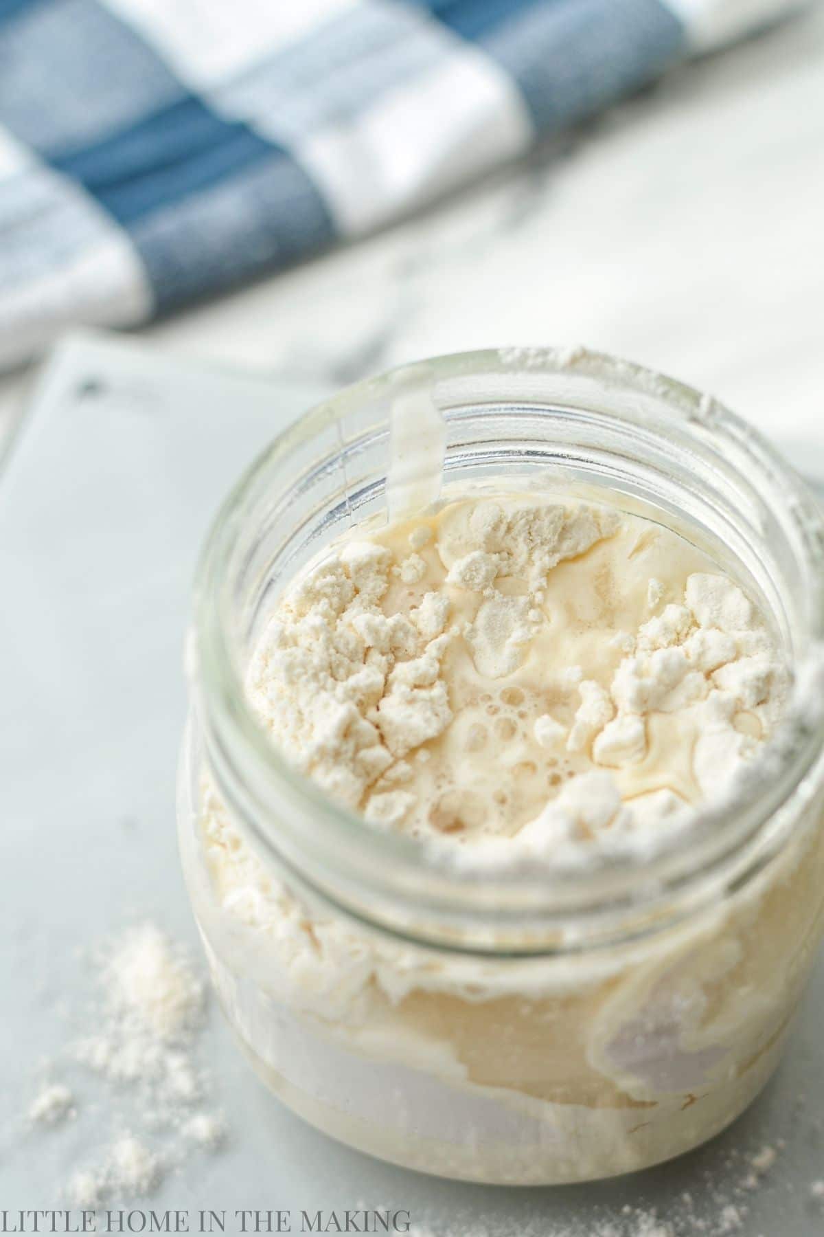 A small jar of sourdough starter, recently fed with flour and water.