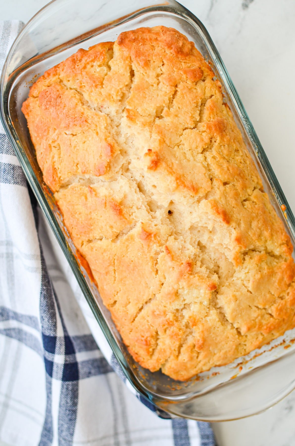 A loaf of sourdough beer bread in a glass loaf pan.